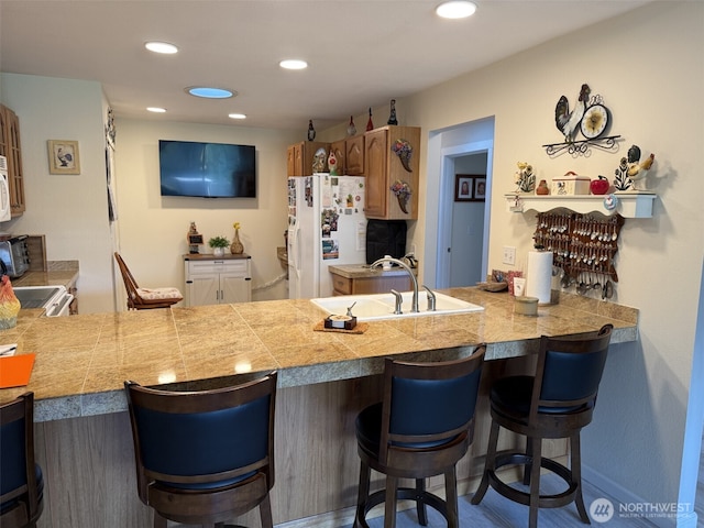 2748 SW 327th St S, Federal Way, WA 98023 - kitchen with a peninsula, white appliances, tile counters, recessed lighting, and a kitchen bar