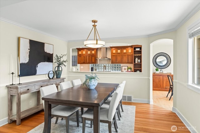 2906W Eaton St, Seattle, WA 98199 - dining area with light wood-type flooring, arched walkways, and ornamental molding