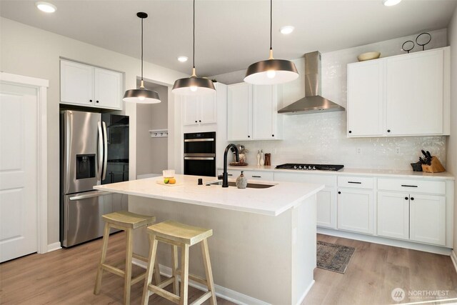 2405 NE Waterlily Way, Poulsbo, WA 98370 - kitchen featuring stainless steel refrigerator with ice dispenser, wall chimney exhaust hood, gas cooktop, light wood-style floors, and recessed lighting