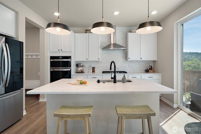 2405 NE Waterlily Way, Poulsbo, WA 98370 - kitchen with appliances with stainless steel finishes, wall chimney range hood, light wood-type flooring, backsplash, and a kitchen bar
