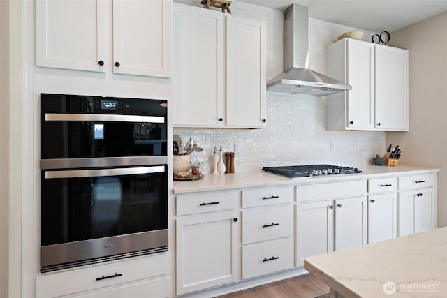2405 NE Waterlily Way, Poulsbo, WA 98370 - kitchen featuring wall chimney exhaust hood, stainless steel appliances, white cabinetry, decorative backsplash, and light stone counters