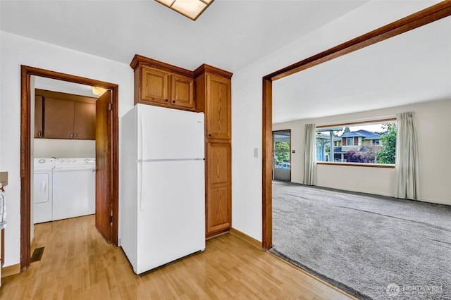 4723 50th Ave SW, Seattle, WA 98116 - kitchen with freestanding refrigerator, washing machine and dryer, light wood-style flooring, and brown cabinets