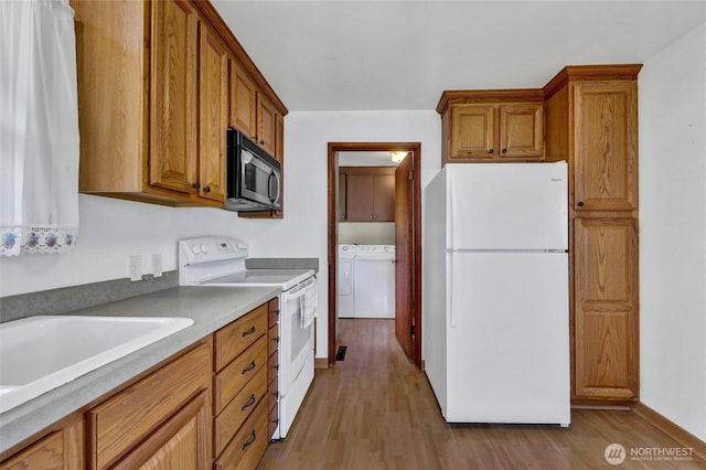 4723 50th Ave SW, Seattle, WA 98116 - kitchen with white appliances, separate washer and dryer, brown cabinetry, and light wood finished floors