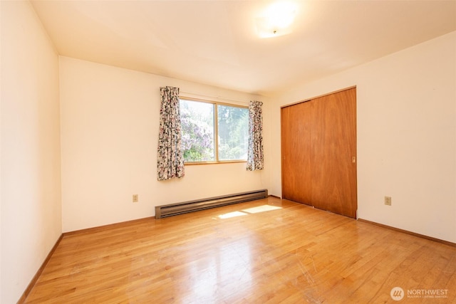 723 W 15th St, Port Angeles, WA 98363 - unfurnished bedroom with a baseboard heating unit, wood finished floors, and a closet