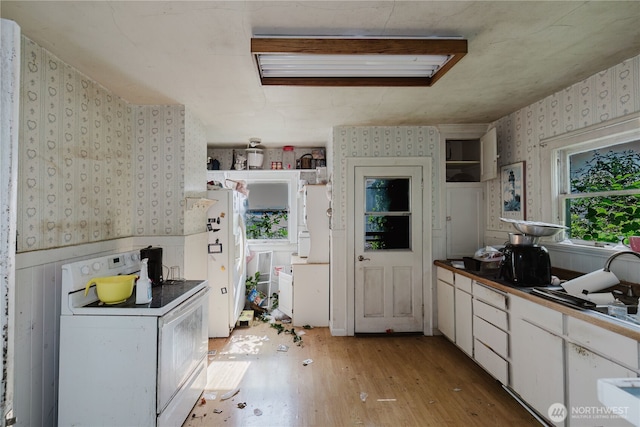 7936 E Main St, Port Orchard, WA 98366 - kitchen featuring wallpapered walls, white appliances, light wood finished floors, white cabinetry, and a wainscoted wall