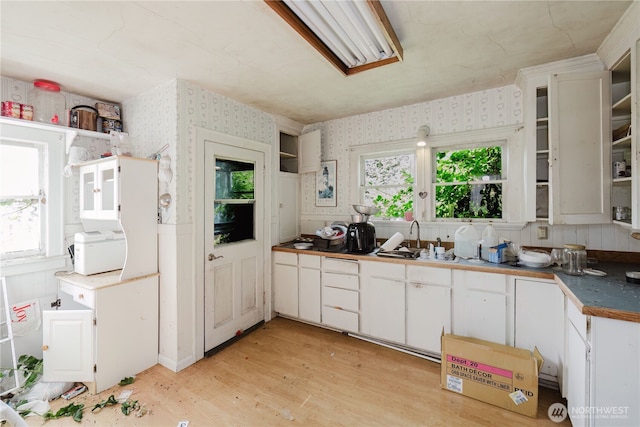 7936 E Main St, Port Orchard, WA 98366 - kitchen with wallpapered walls, white cabinets, light wood finished floors, and dark countertops