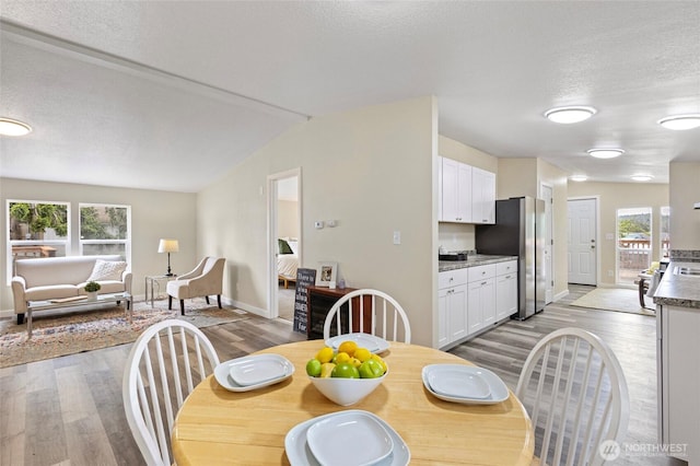 1320 N Oak Harbor St Unit 1, Oak Harbor, WA 98277 - dining area featuring light wood finished floors, plenty of natural light, a textured ceiling, and vaulted ceiling