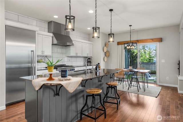 2211 56th St SE, Auburn, WA 98092 - kitchen with stainless steel built in refrigerator, wall chimney exhaust hood, white cabinets, backsplash, and a kitchen island with sink