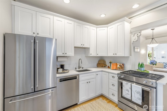 2707 4th Ave W, Seattle, WA 98119 - kitchen featuring stainless steel appliances, light countertops, white cabinetry, tasteful backsplash, and light wood-type flooring