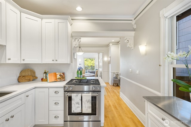 2707 4th Ave W, Seattle, WA 98119 - kitchen with gas range, white cabinets, backsplash, light wood-style flooring, and recessed lighting