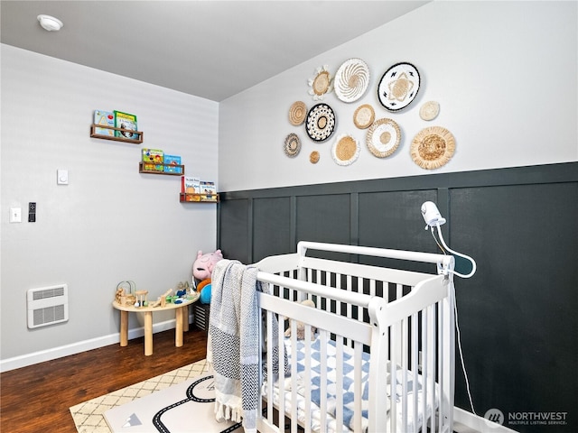 800 96th Ave NE Unit H202, Lake Stevens, WA 98258 - bedroom featuring heating unit, a crib, wood finished floors, a decorative wall, and a wainscoted wall
