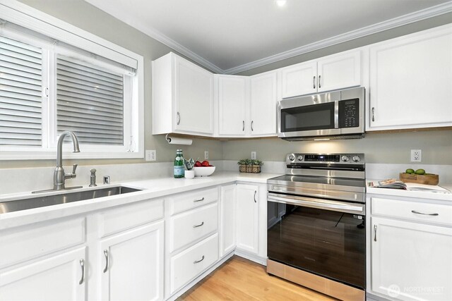 9414 Hancock Ave SE, Snoqualmie, WA 98065 - kitchen with appliances with stainless steel finishes, white cabinets, light countertops, ornamental molding, and light wood-style floors