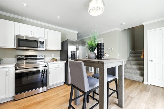 9414 Hancock Ave SE, Snoqualmie, WA 98065 - kitchen with stainless steel appliances, ornamental molding, light wood-style floors, white cabinets, and recessed lighting