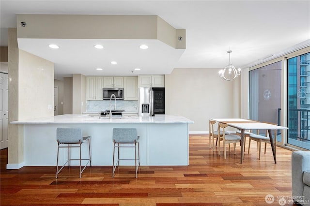177 107th Ave NE Unit 1012, Bellevue, WA 98004 - kitchen with appliances with stainless steel finishes, light wood-type flooring, decorative backsplash, a peninsula, and a breakfast bar