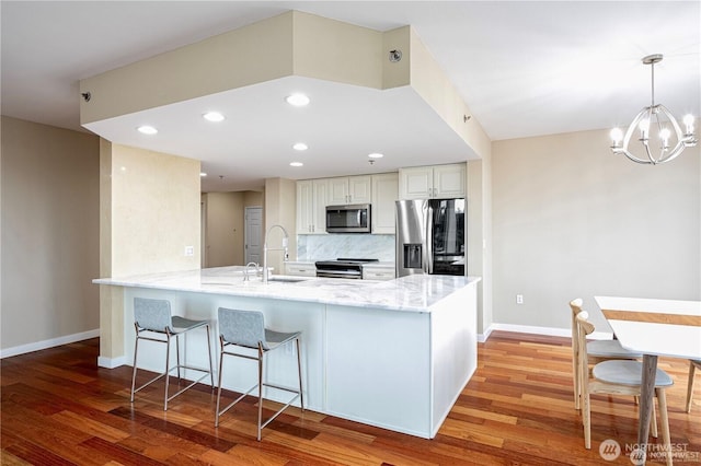 177 107th Ave NE Unit 1012, Bellevue, WA 98004 - kitchen featuring stainless steel appliances, a peninsula, light stone countertops, light wood-style floors, and recessed lighting