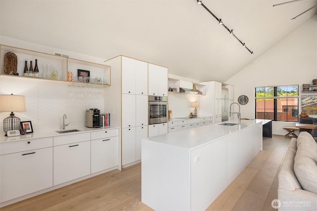 4566 Flying Goat Ave NE Unit C220, Bainbridge Island, WA 98110 - kitchen with open shelves, oven, light wood-type flooring, backsplash, and high vaulted ceiling