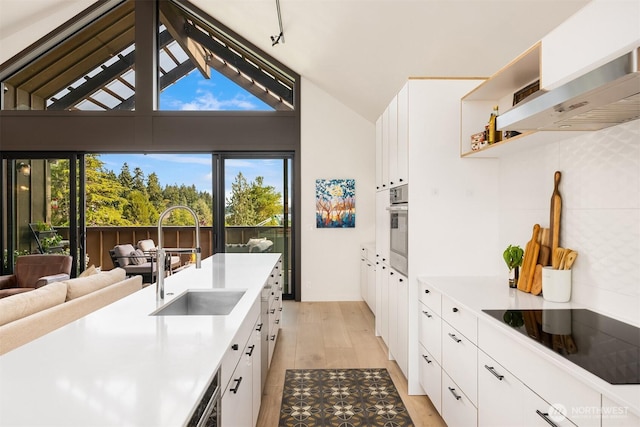 4566 Flying Goat Ave NE Unit C220, Bainbridge Island, WA 98110 - kitchen with black electric cooktop, ventilation hood, white cabinetry, light countertops, and lofted ceiling