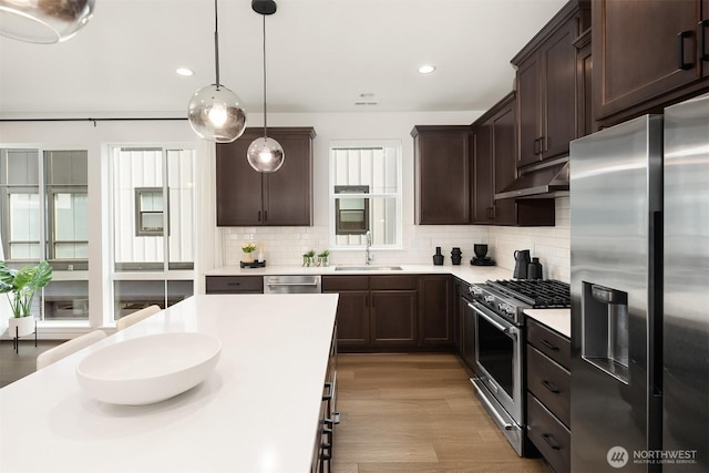 21822 25th Ave SE Unit B, Bothell, WA 98021 - kitchen with stainless steel appliances, under cabinet range hood, dark brown cabinetry, light countertops, and backsplash