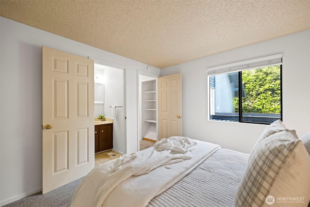 606 N State St, Bellingham, WA 98225 - bedroom featuring a textured ceiling, connected bathroom, a walk in closet, and light carpet