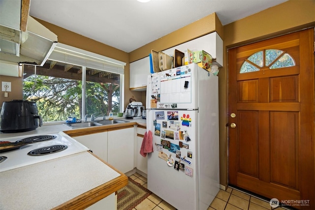 606 N State St, Bellingham, WA 98225 - kitchen with freestanding refrigerator, white cabinetry, light tile patterned flooring, and light countertops