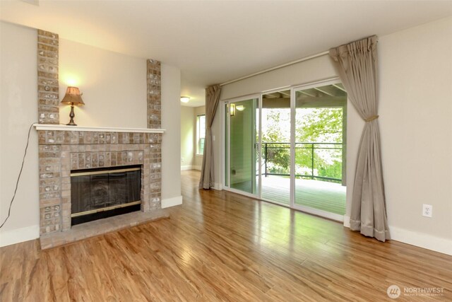 3008 N Narrows Dr Unit B102, Tacoma, WA 98407 - unfurnished living room featuring a brick fireplace and wood finished floors