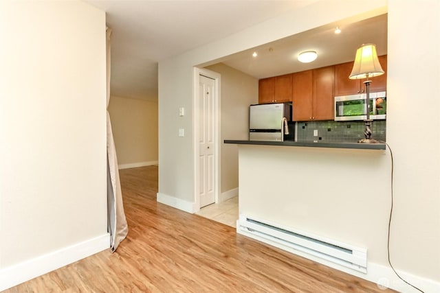 3008 N Narrows Dr Unit B102, Tacoma, WA 98407 - kitchen featuring stainless steel appliances, a baseboard heating unit, dark countertops, light wood finished floors, and decorative backsplash