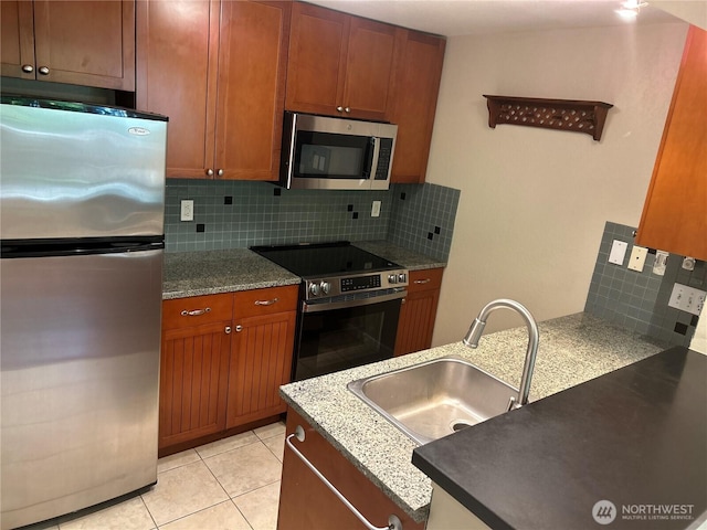 3008 N Narrows Dr Unit B102, Tacoma, WA 98407 - kitchen featuring stainless steel appliances, tasteful backsplash, brown cabinets, and dark stone counters