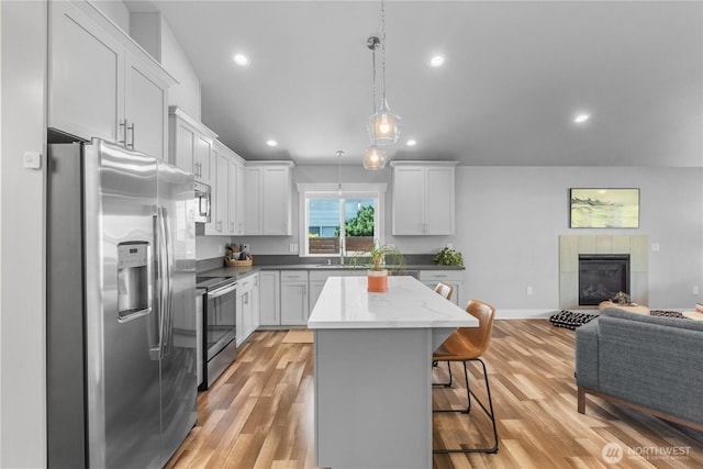 477 Ocean Shores Blvd SW, Ocean Shores, WA 98569 - kitchen featuring appliances with stainless steel finishes, open floor plan, a breakfast bar, a center island, and light wood-style floors