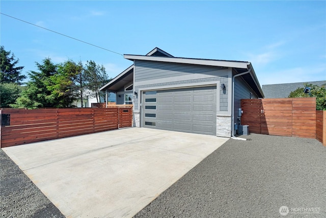 477 Ocean Shores Blvd SW, Ocean Shores, WA 98569 - view of side of home featuring driveway, an attached garage, a gate, and stone siding