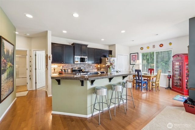 26707 NE 144th Ct, Duvall, WA 98019 - kitchen with appliances with stainless steel finishes, a kitchen bar, light wood-style floors, backsplash, and recessed lighting