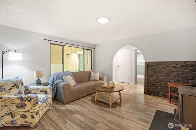 8200 NE View Ridge Ln, Poulsbo, WA 98370 - living room featuring arched walkways, light wood-style flooring, and a textured ceiling