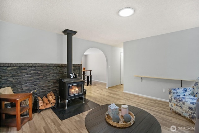 8200 NE View Ridge Ln, Poulsbo, WA 98370 - living area with a wood stove, arched walkways, light wood-type flooring, and a textured ceiling
