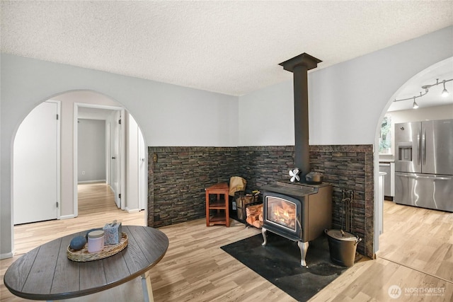 8200 NE View Ridge Ln, Poulsbo, WA 98370 - living area featuring arched walkways, a wood stove, wood finished floors, and a textured ceiling