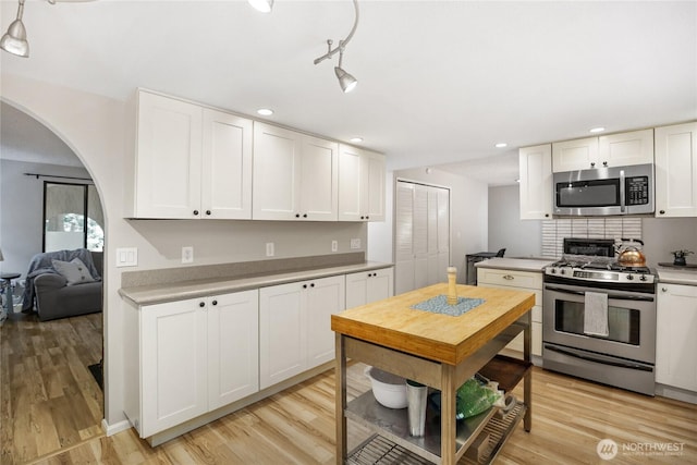 8200 NE View Ridge Ln, Poulsbo, WA 98370 - kitchen featuring appliances with stainless steel finishes, light countertops, arched walkways, white cabinets, and recessed lighting