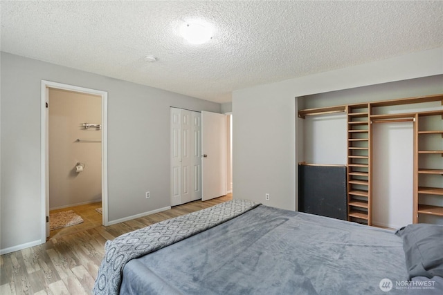 8200 NE View Ridge Ln, Poulsbo, WA 98370 - bedroom with wood finished floors, a textured ceiling, two closets, and ensuite bath