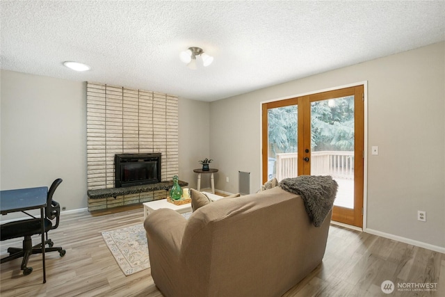 8200 NE View Ridge Ln, Poulsbo, WA 98370 - living room with french doors, light wood-type flooring, a textured ceiling, and a brick fireplace