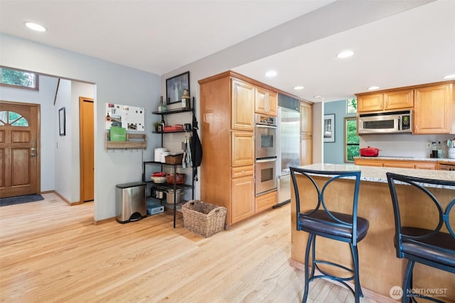 24230 218th Ave SE, Maple Valley, WA 98038 - kitchen with stainless steel appliances, a kitchen breakfast bar, light wood-style flooring, recessed lighting, and plenty of natural light