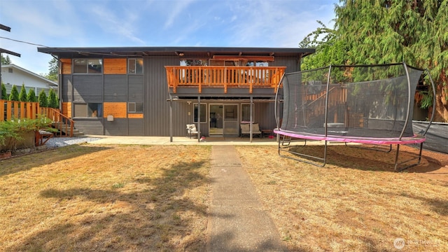 501 143rd St S, Tacoma, WA 98444 - back of property featuring a trampoline, a lawn, a patio, and a wooden deck