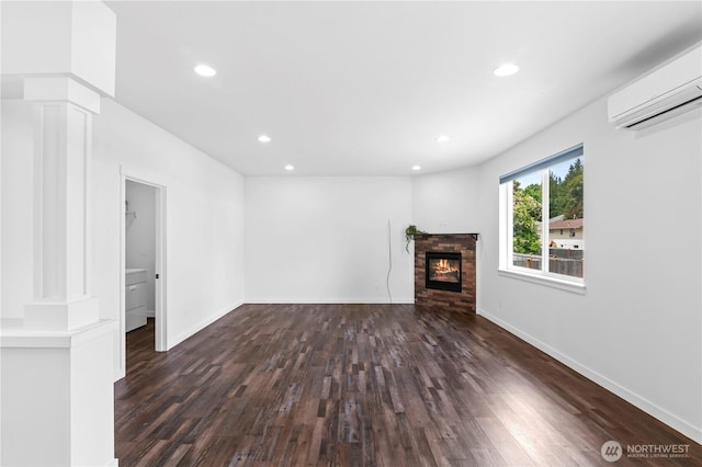 1611 Austin Ave, Snohomish, WA 98290 - unfurnished living room with ornate columns, a wall mounted AC, wood finished floors, recessed lighting, and a glass covered fireplace