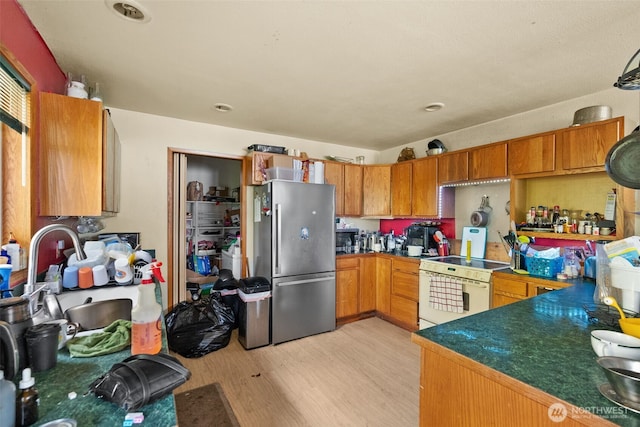 80 E Rose Point Ln, Belfair, WA 98528 - kitchen featuring freestanding refrigerator, white electric range, light wood-style flooring, brown cabinetry, and dark countertops
