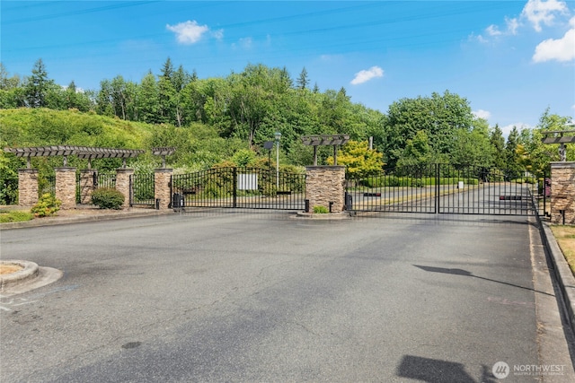 3006 SE 8th St Unit 2120, Renton, WA 98058 - view of asphalt street with a gate, curbs, a gated entry, and view of scattered trees