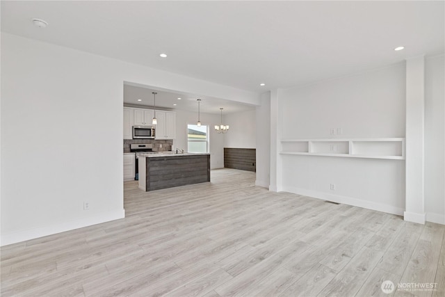 2204 Dublin Pl, Anacortes, WA 98221 - unfurnished living room featuring light wood-style flooring, recessed lighting, and a chandelier