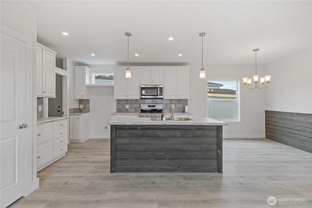 2204 Dublin Pl, Anacortes, WA 98221 - kitchen featuring stainless steel microwave, stove, white cabinetry, tasteful backsplash, and light wood-style floors