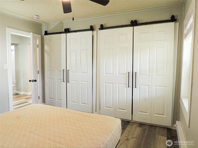 14806 131st Ave SE, Renton, WA 98058 - bedroom with a barn door, dark wood finished floors, crown molding, baseboard heating, and ceiling fan