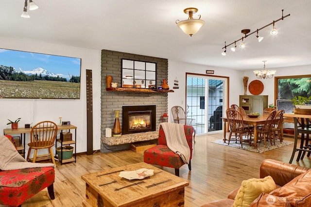 2815 Willis St, Bellingham, WA 98225 - living area featuring track lighting, a chandelier, a brick fireplace, and light wood-type flooring