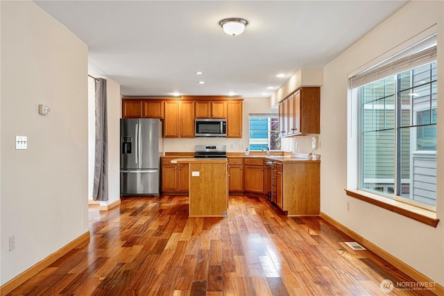 10736 Whitman Ave N, Seattle, WA 98133 - kitchen featuring appliances with stainless steel finishes, wood finished floors, a center island, light countertops, and recessed lighting