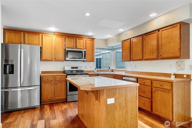 10736 Whitman Ave N, Seattle, WA 98133 - kitchen with appliances with stainless steel finishes, light wood-type flooring, brown cabinetry, a center island, and recessed lighting
