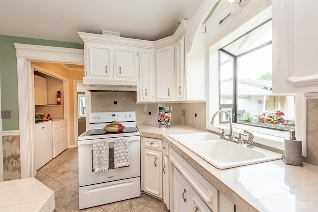 2130 W 4th, Port Angeles, WA 98363 - kitchen with white range with electric stovetop, under cabinet range hood, washing machine and clothes dryer, light countertops, and white cabinets