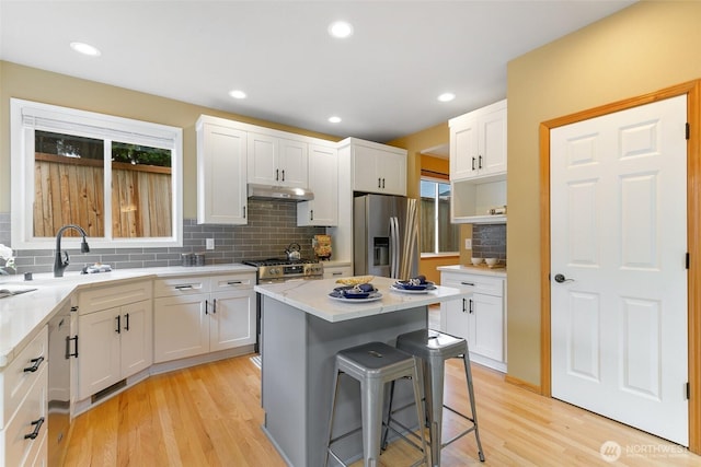18328 10th Dr SE, Bothell, WA 98012 - kitchen featuring stainless steel appliances, under cabinet range hood, a kitchen bar, white cabinetry, and recessed lighting