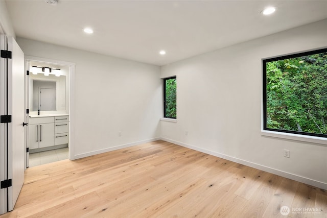 5606 23rd Ave SW, Seattle, WA 98106 - unfurnished bedroom with multiple windows, light wood-style floors, recessed lighting, and connected bathroom